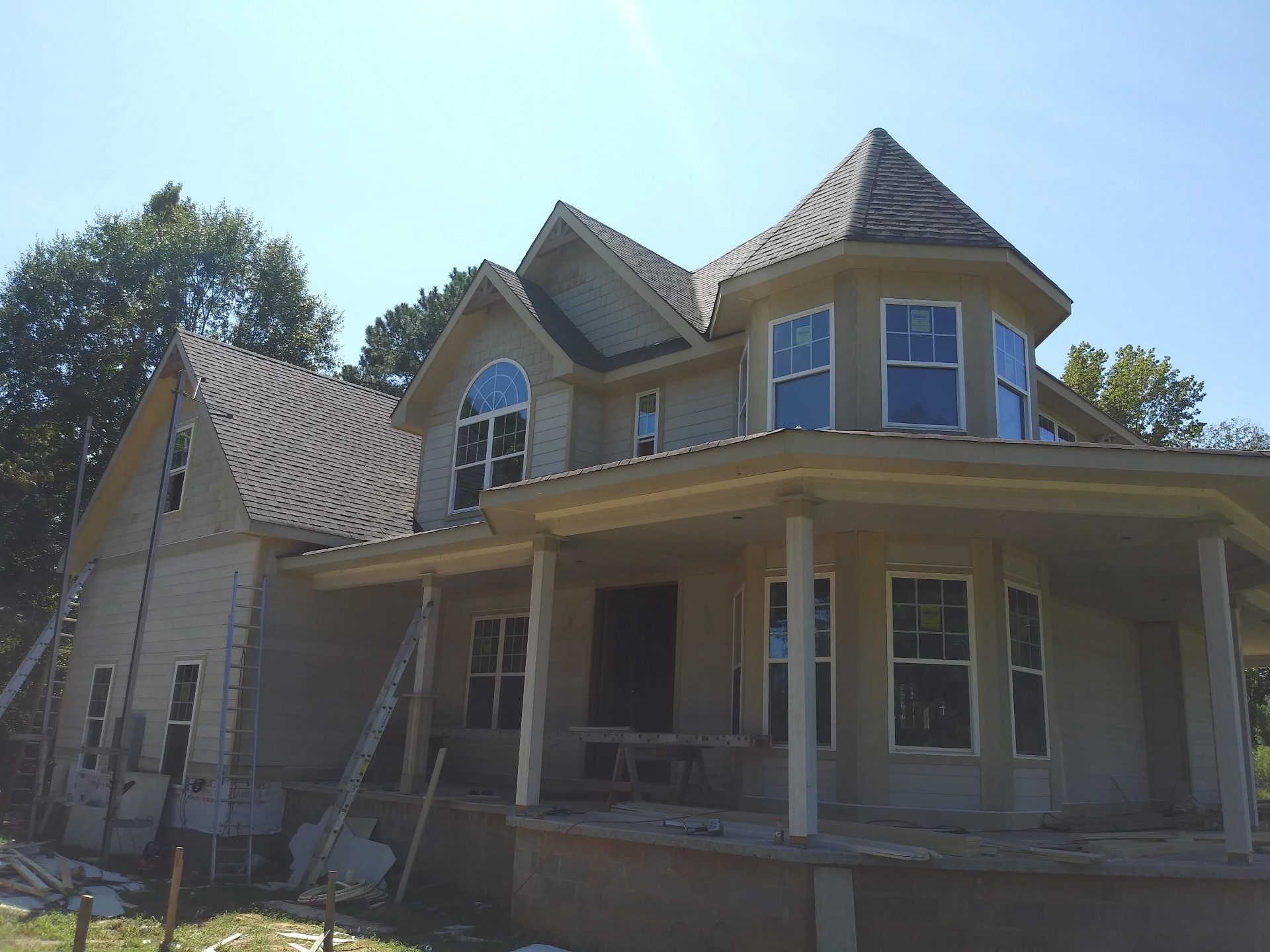 Completed structural framing and roof system of a custom home with turret and gables